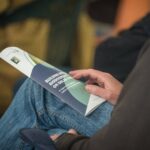 The Building Better Biodiversity on Solar Farms Guide rests on a person's knee