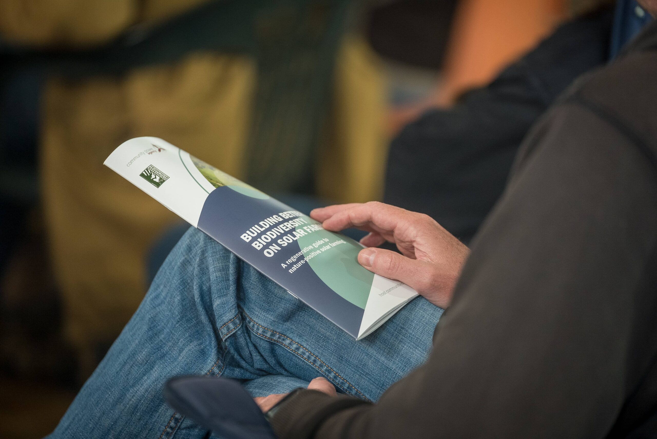 The Building Better Biodiversity on Solar Farms Guide rests on a person's knee