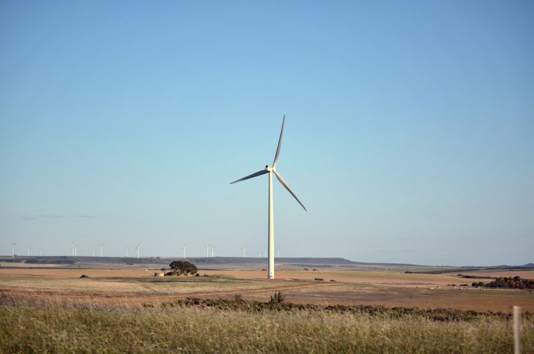 A single wind turbine standing in a dry. arid, regional Australian landscape.